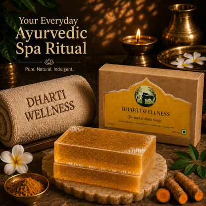 Dharti Wellness Turmeric Bath Soap shown with its kraft paper box and two stacked bars of golden-yellow soap on a stone platter, surrounded by spa props including a rolled towel, curry powder, turmeric roots, flowers, and brass vessels in a warm, atmospheric setting.